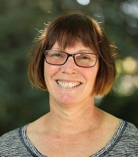 Headshot of Megan Banks smiling in front of blurred foliage